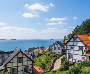 The Namhae German Village in South Korea, with its distinctive white and orange timber-framed houses on a hill overlooking the ocean.