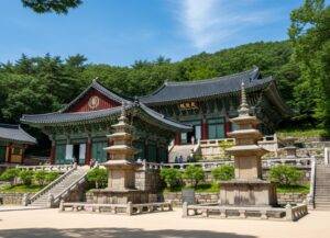 The historic Bulguksa Temple in Gyeongju on a sunny summer day, with its traditional wooden architecture surrounded by vibrant green trees.