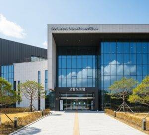 The modern architectural exterior of the Gochang Dolmen Museum on a sunny day, with its name written in both English and Korean above the entrance.