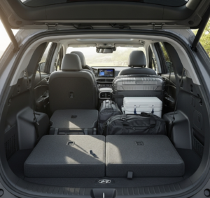  The spacious rear cargo area of a 2024 Hyundai Santa Fe with the third-row seats folded flat, filled with luggage.