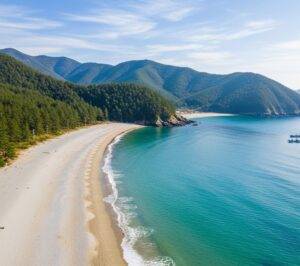 The serene Sangju Silver Sand Beach in Namhae, with its calm, clear water and soft, silvery sand, enclosed by a green, mountainous coastline.