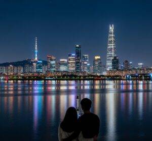 A couple enjoying the romantic night view of the Seoul skyline from a Han River cruise ship.