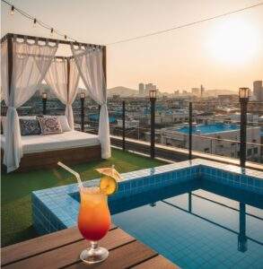 A vibrant, high-contrast photo of the "HOTEL 707" rooftop at sunset, featuring a colorful tropical cocktail on a wooden table next to a small, blue-tiled pool, with a white-curtained daybed in the background.