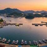 Tongyeong Travel: Scenic panoramic view of Tongyeong Gangguan Harbor and Hallyeohaesang National Park at sunset.