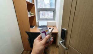 First-person POV of a person holding a T-Money card and a key in front of a small Goshiwon room door in Korea.