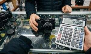 A first-person point-of-view photograph from a Seoul electronics market, looking down at a cluttered glass counter where a shopkeeper holds a black Nikon FM2 camera and the user holds a calculator displaying 450,000.