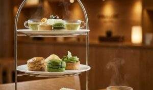 A premium Korean afternoon tea set with green tea and various desserts on a tiered stand inside the cozy and luxurious O'Sulloc 1979 tea house in Seoul.