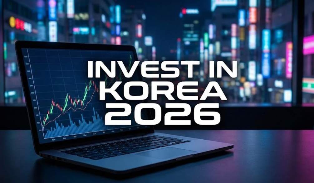 A laptop displaying a stock market chart with the bold text "INVEST IN KOREA 2026" overlaid, set against a blurred nighttime view of Seoul.