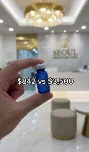 Hand holding a Rejuran Healer vial in a Seoul clinic. Text overlay: "$842 vs $3,500".