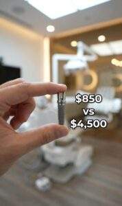 A first-person view of a hand holding a single dental implant, with the text overlay "$850 VS $4,500" in a modern dental clinic setting.